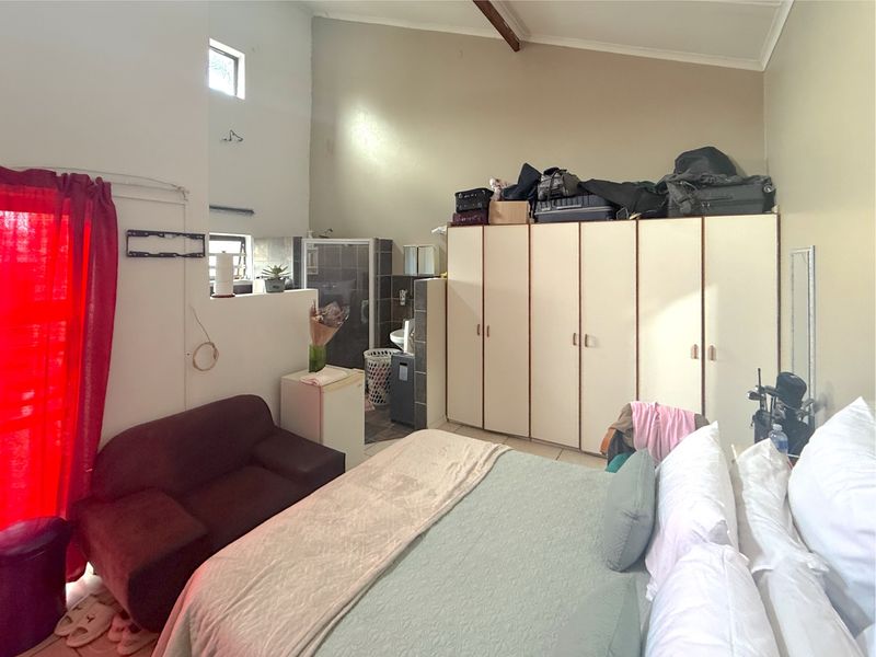 Spacious bedroom featuring vaulted ceilings, built-in cupboards, and an integrated en-suite shower area with tiled flooring.