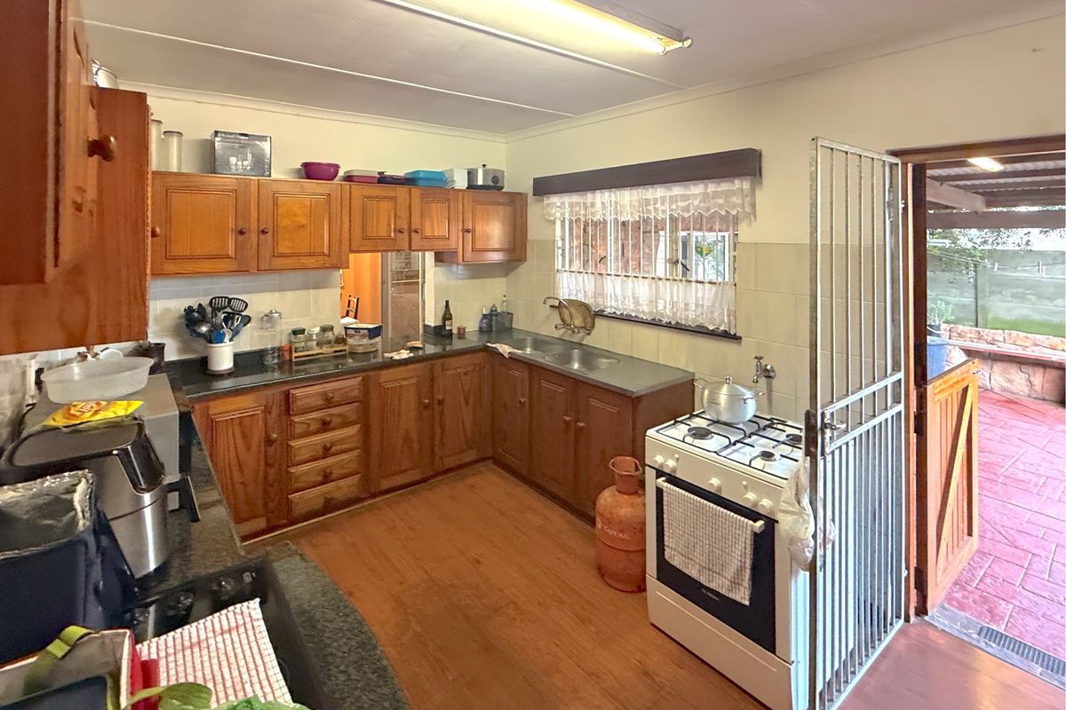 A functional kitchen featuring wooden cabinetry, a gas stove, and direct access to an outdoor patio area through a security gate.