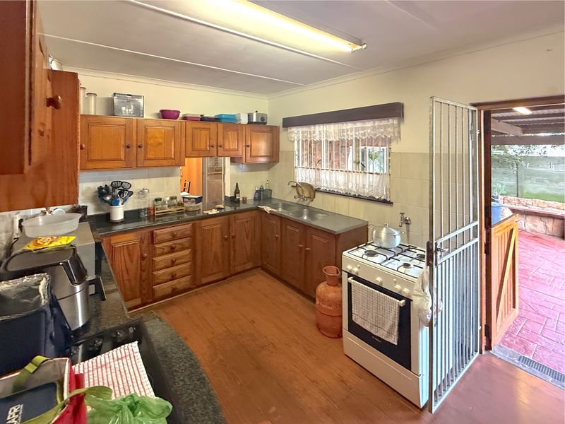 A functional kitchen featuring wooden cabinetry, a gas stove, and direct access to an outdoor patio area through a security gate.