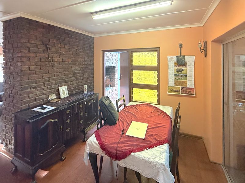 Dining room featuring an exposed brick wall, tiled flooring, and access to an outdoor area through a sliding glass door.