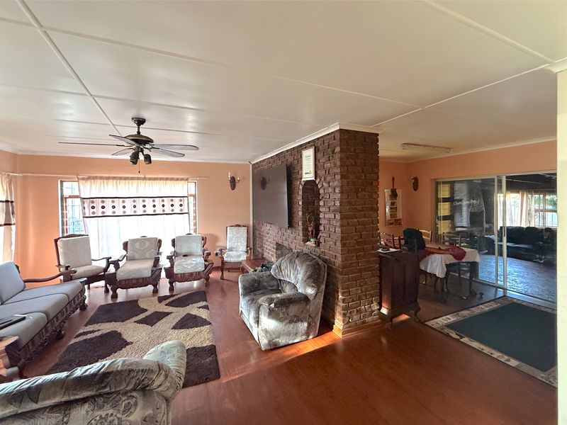 Spacious open-plan living and dining area featuring an exposed brick wall, laminate flooring, and sliding glass doors leading to the outdoor space.