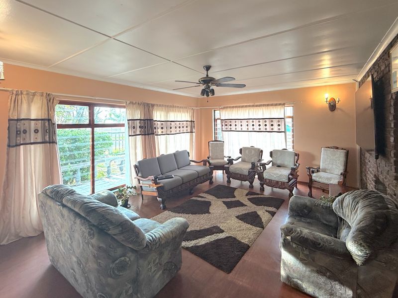 Spacious living room featuring an exposed brick accent wall, ceiling fan, and large sliding glass doors providing access to the outdoor area.