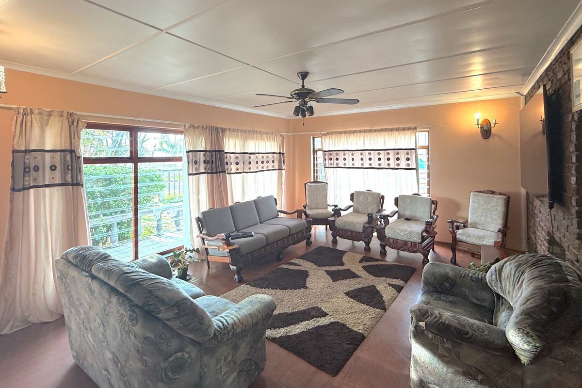 Spacious living room featuring an exposed brick accent wall, ceiling fan, and large sliding glass doors providing access to the outdoor area.