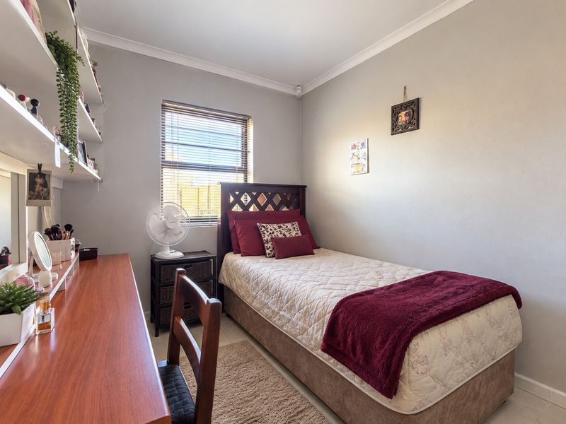 A well-maintained bedroom featuring built-in shelving, neutral wall finishes, and a window fitted with venetian blinds.
