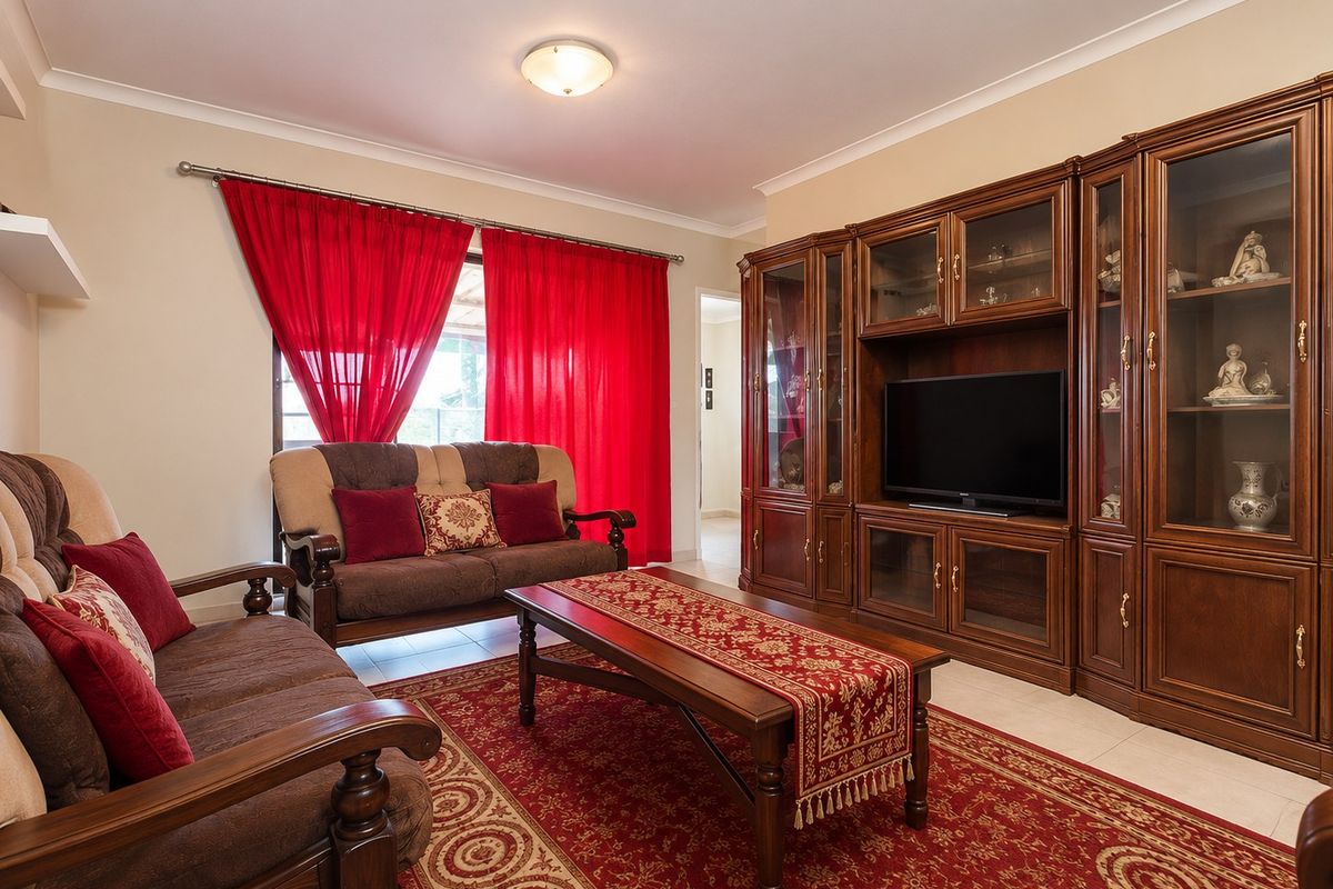 A living room featuring tiled flooring, coving, and extensive built-in wooden cabinetry providing ample storage and display space.