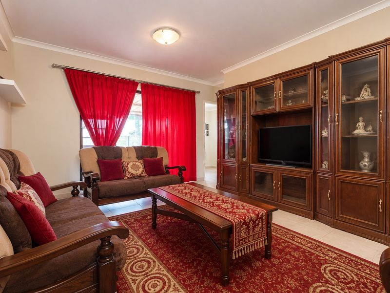A living room featuring tiled flooring, coving, and extensive built-in wooden cabinetry providing ample storage and display space.