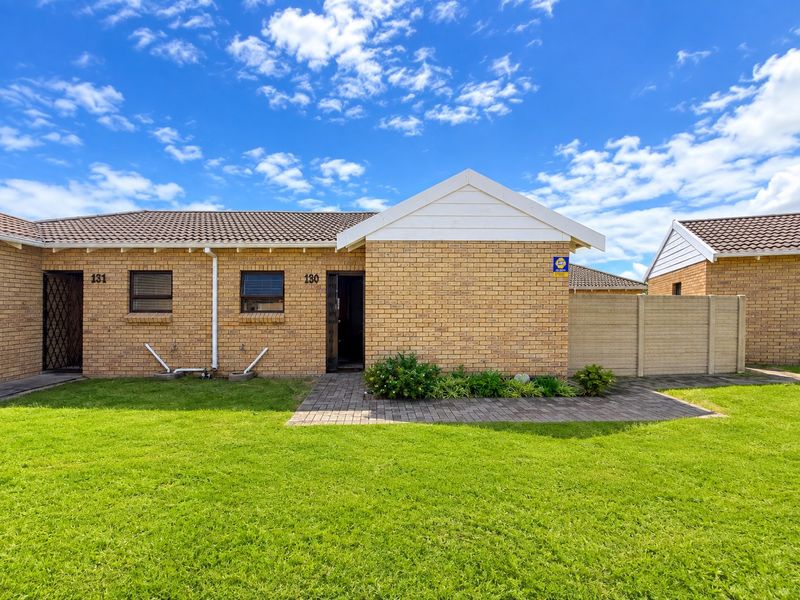 Front exterior view of a face brick townhouse unit featuring a paved walkway, small garden area, and secure entrance.