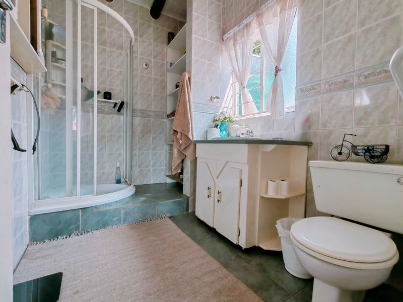 A functional bathroom featuring a corner shower enclosure, vanity cabinet with integrated basin, and tiled finishes throughout.