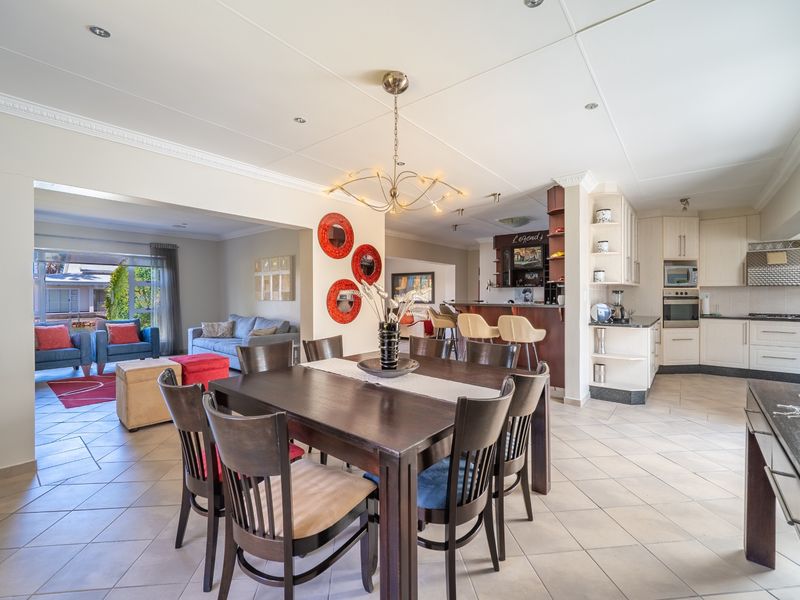 Spacious open-plan living area featuring a dining space, a well-equipped kitchen with built-in appliances, and a breakfast bar, flowing into a comfortable lounge.