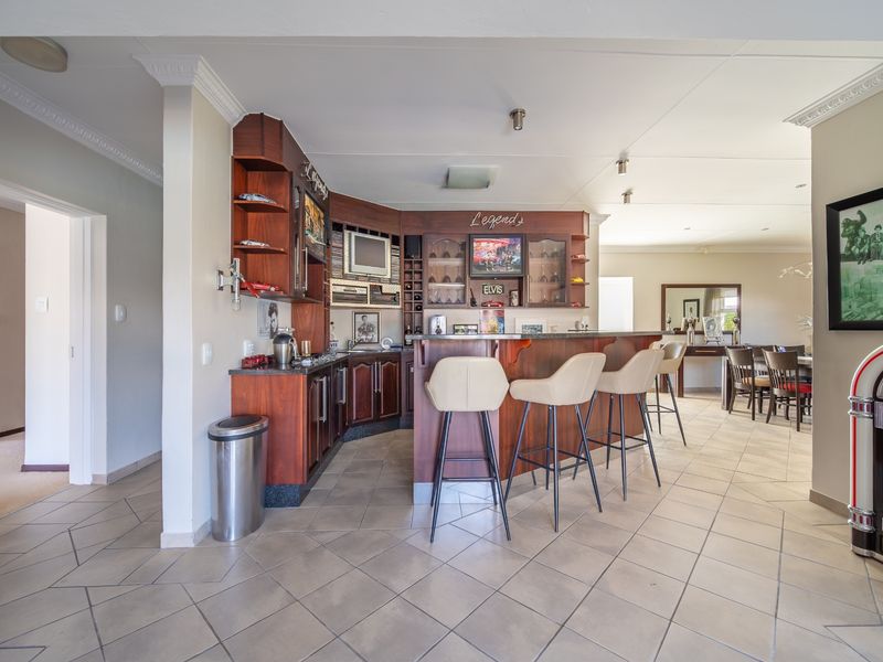 A dedicated home bar area featuring custom built-in cabinetry, a bar counter, and tiled flooring, seamlessly integrated into the open-plan living space.