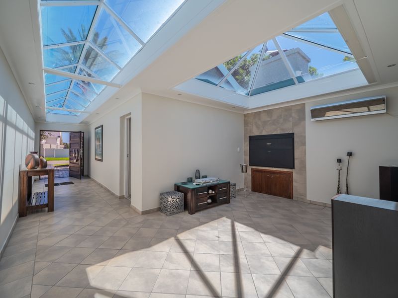 Bright and airy living room featuring expansive skylights, tiled flooring, and a built-in fireplace, creating a welcoming and well-lit space.