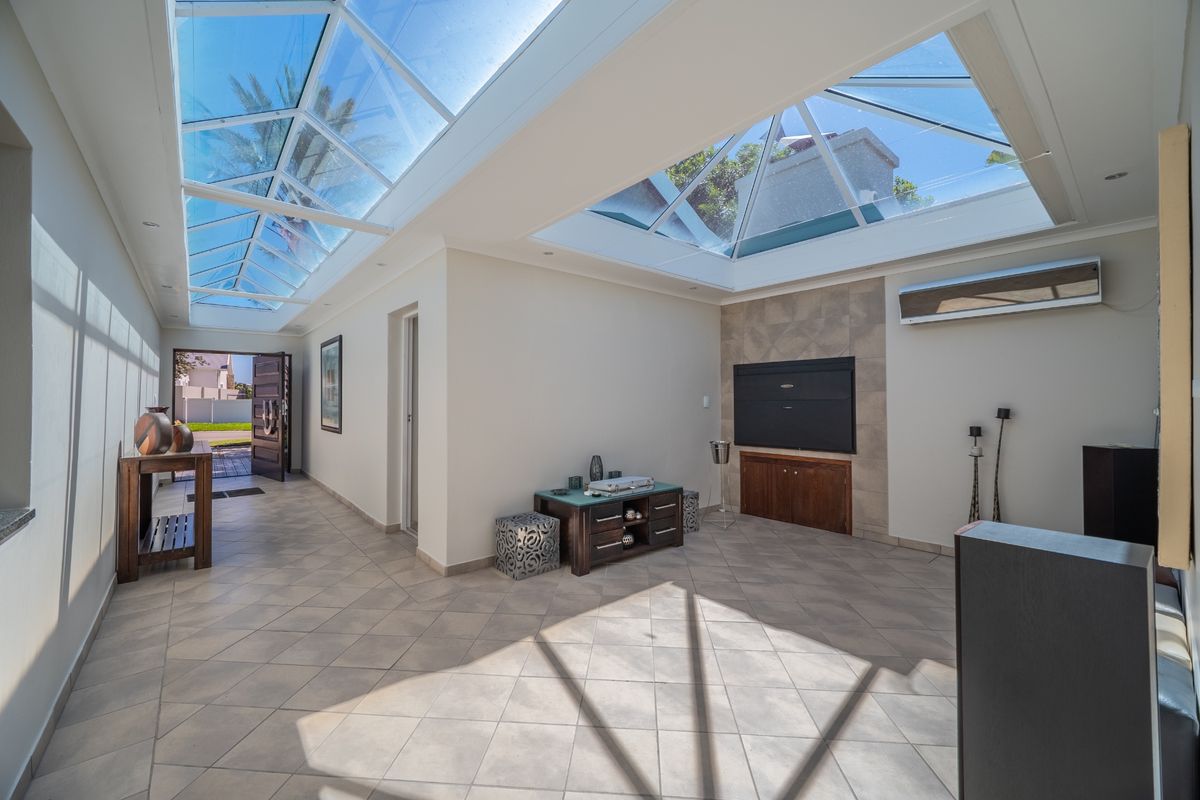 Bright and airy living room featuring expansive skylights, tiled flooring, and a built-in fireplace, creating a welcoming and well-lit space.