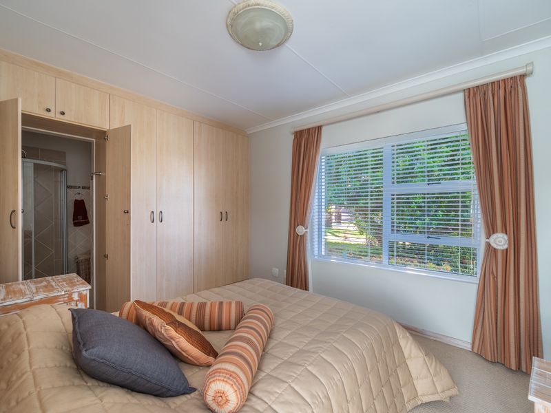 A well-lit bedroom featuring built-in wooden cupboards, neutral carpeting, and direct access to an en-suite bathroom.
