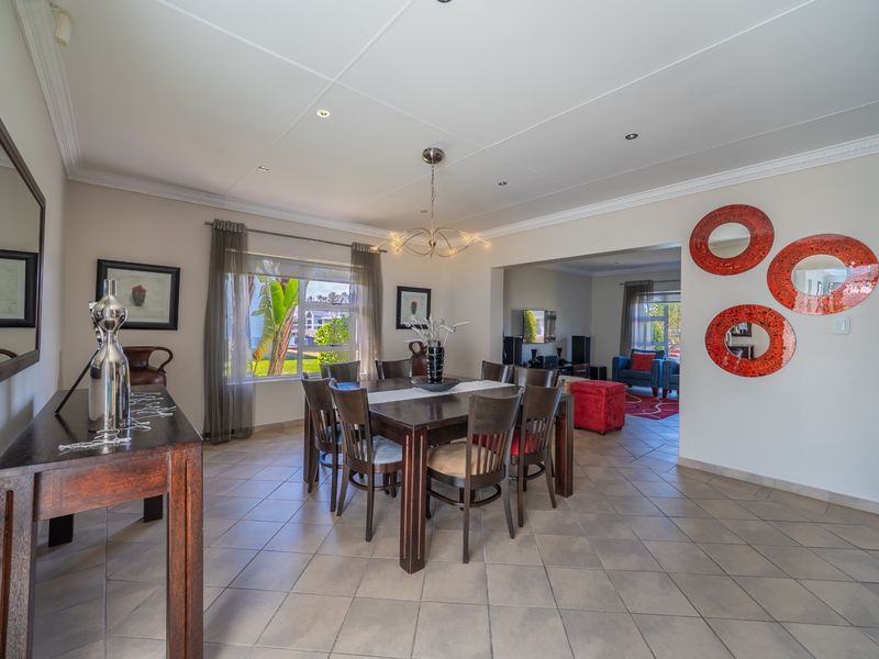 Spacious open-plan dining and living area featuring neutral tiled flooring, recessed lighting, and crown molding, creating a bright and connected living space.