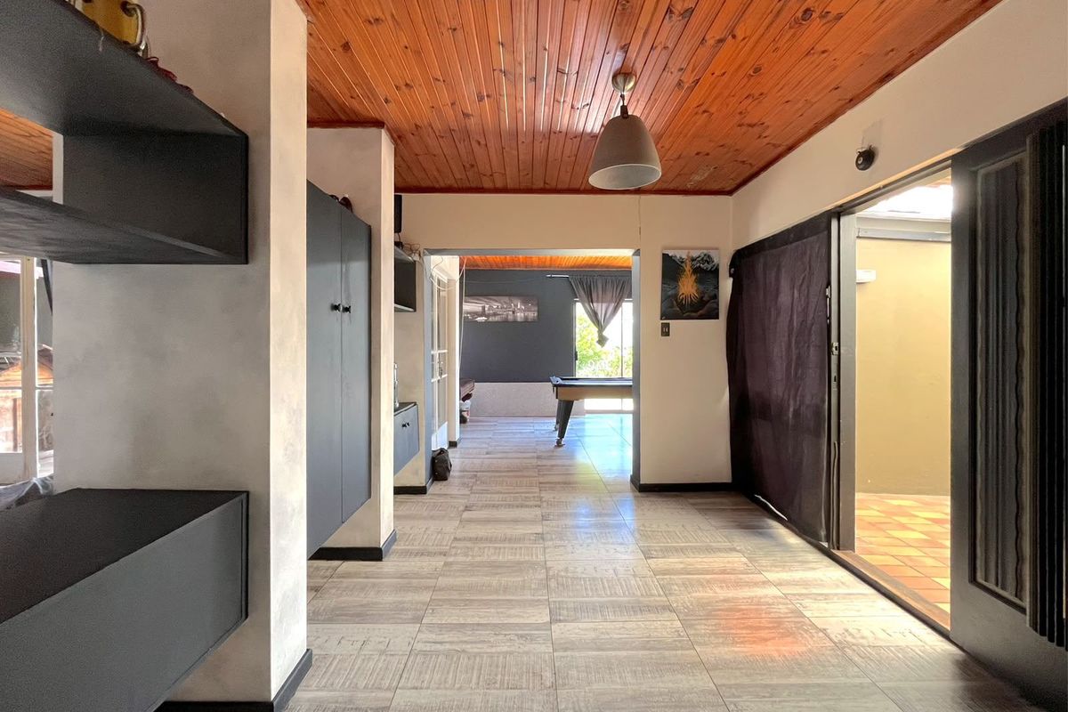 Spacious living area featuring timber tongue and groove ceilings, ceramic floor tiles, and direct access to an outdoor patio through sliding glass doors.