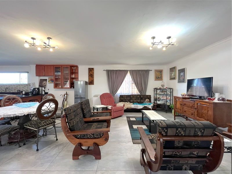 Spacious open-plan living and dining area featuring tiled flooring and integrated kitchen cabinetry, offering a versatile layout for family living.