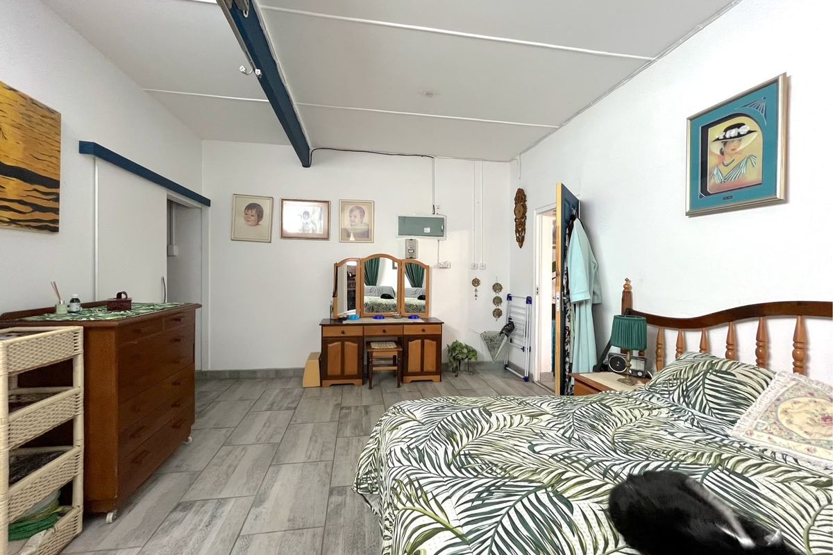 Spacious bedroom featuring tiled flooring, exposed ceiling beams, and functional layout with direct access to adjacent rooms.