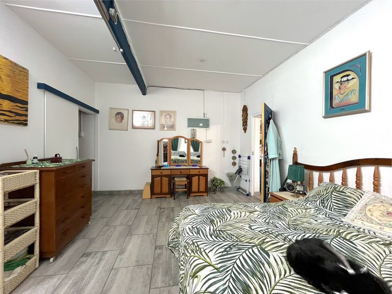 Spacious bedroom featuring tiled flooring, exposed ceiling beams, and functional layout with direct access to adjacent rooms.