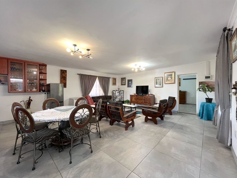 Spacious open-plan living and dining area featuring large format floor tiles and built-in cabinetry, offering a versatile layout for family living.