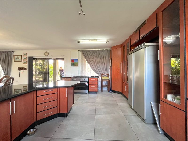 Spacious kitchen featuring cherry-wood cabinetry, granite countertops, tiled flooring, and a built-in gas stove with direct access to the outdoor area.
