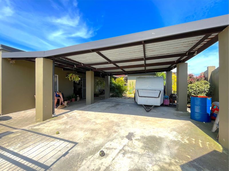 A spacious covered carport area featuring a concrete slab floor and sturdy steel support columns, providing ample sheltered parking space.