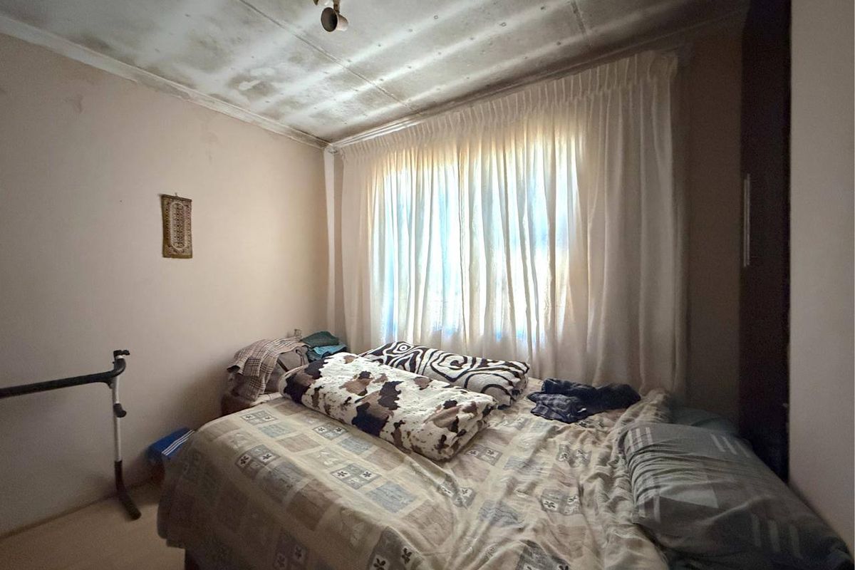 A bedroom featuring a built-in cupboard and significant water damage visible on the ceiling, requiring maintenance and cosmetic repair.