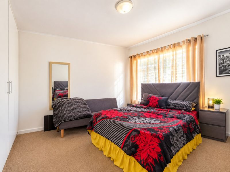 A well-maintained bedroom featuring neutral walls, carpet flooring, and a spacious built-in wardrobe, offering a comfortable and functional living space.