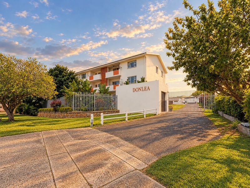 Front view of the Donlea apartment complex featuring a secure gated entrance, paved driveway, and well-maintained landscaped grounds.