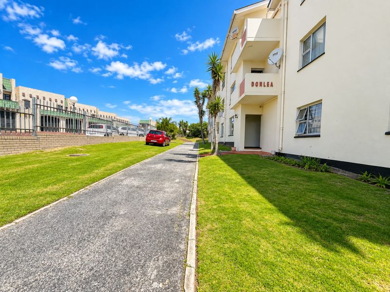 Exterior view of the Donlea apartment complex featuring a paved driveway, well-maintained lawn, and multi-level balconies.