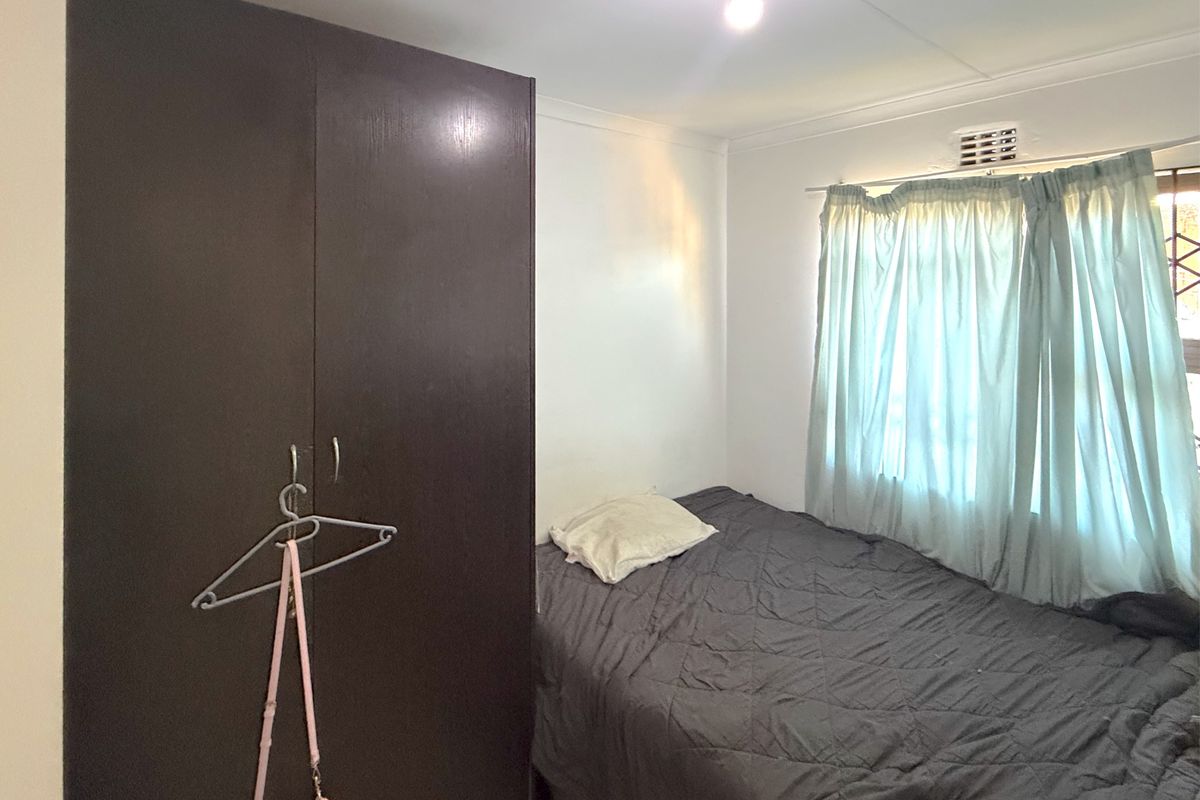 A functional bedroom featuring a built-in wardrobe and a window with natural light.