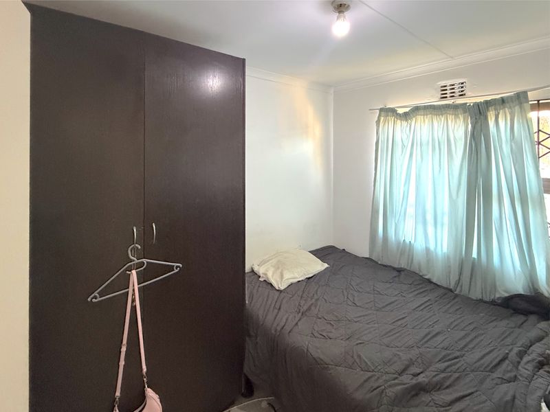 A functional bedroom featuring a built-in wardrobe and a window with natural light.