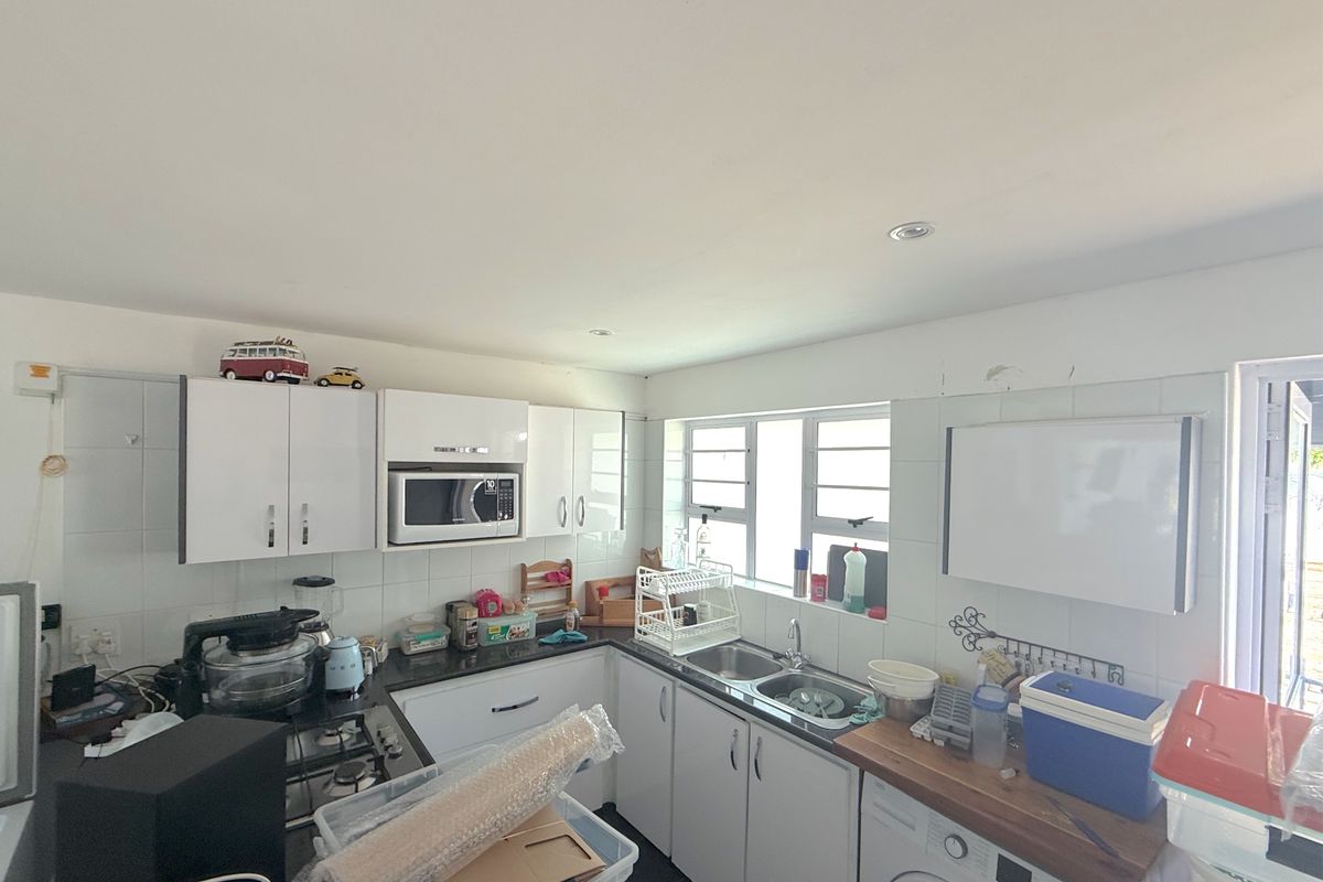 Functional kitchen featuring white cabinetry, granite countertops, a gas hob, built-in microwave, and a double sink with tiled backsplash.