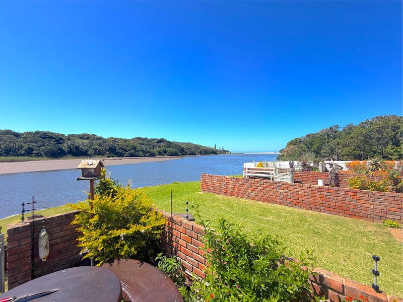 A scenic view overlooking the river and natural landscape from the property's garden area, featuring established brick boundary walls and well-maintained lawn.