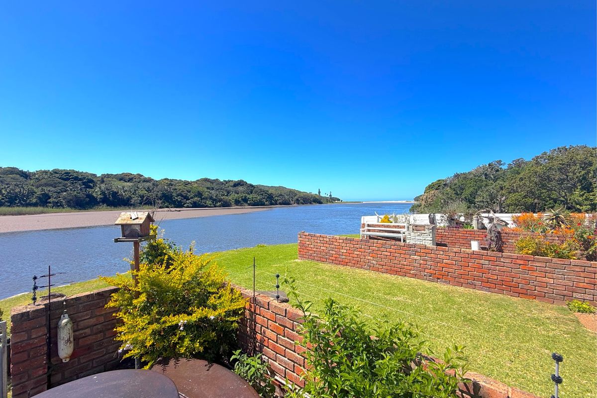 A scenic view overlooking the river and natural landscape from the property's garden area, featuring established brick boundary walls and well-maintained lawn.