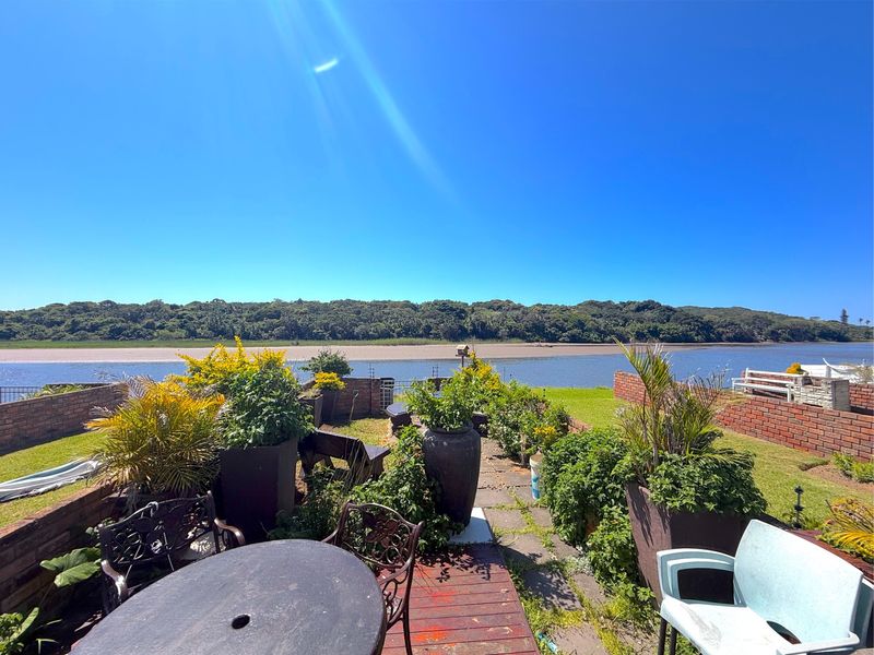 A rear garden area featuring a paved patio, brick boundary walls, and expansive views over the river and natural landscape.