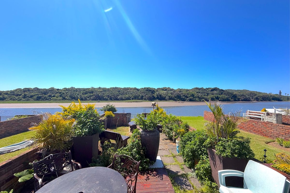 A rear garden area featuring a paved patio, brick boundary walls, and expansive views over the river and natural landscape.