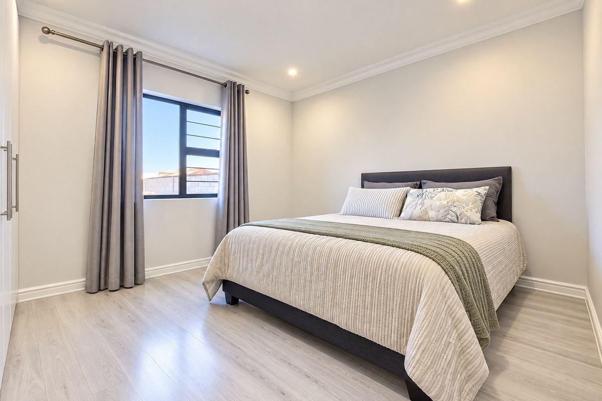A well-maintained bedroom featuring light-toned laminate flooring, recessed downlighting, and a built-in wardrobe.