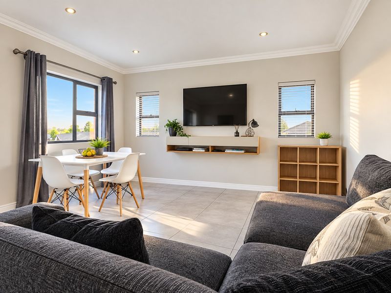 A bright and modern open-plan living and dining area featuring tiled floors, recessed lighting, and a sleek floating media console.