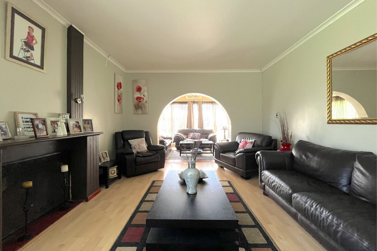 A spacious living room featuring a fireplace, laminate flooring, and a distinctive arched opening leading to an adjacent area.
