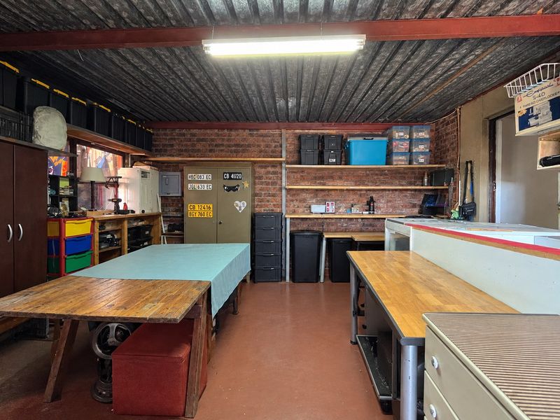 A functional utility or workshop space featuring exposed brick walls, corrugated metal ceiling, and practical built-in shelving, suitable for various hobby or storage uses.