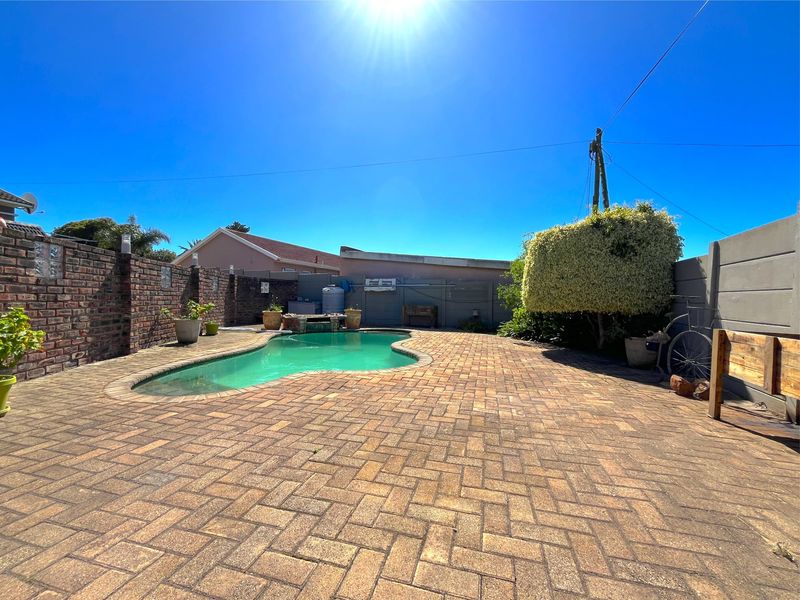 Outdoor pool area featuring a kidney-shaped swimming pool, brick paving, and a brick boundary wall.