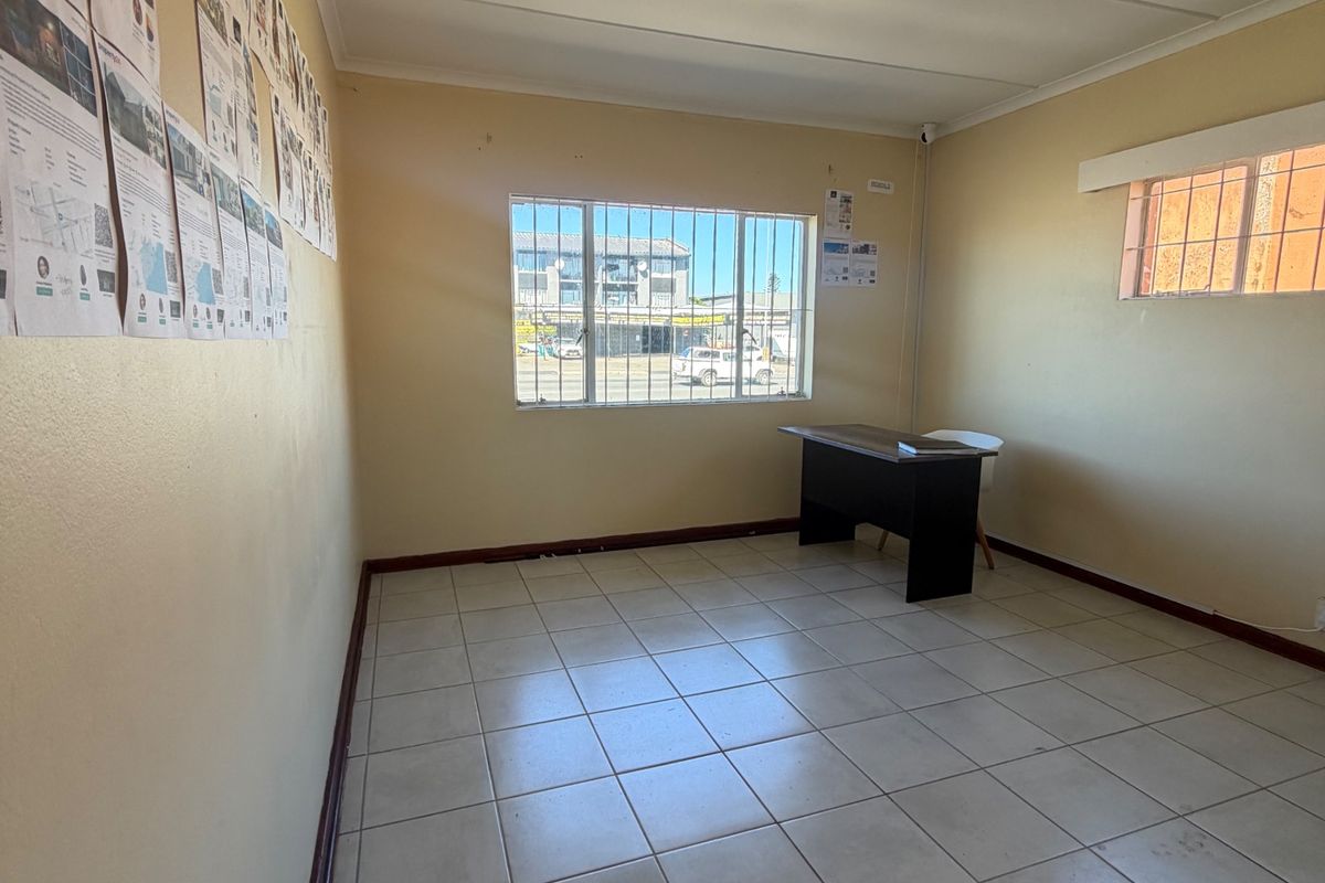 A vacant office space featuring tiled flooring, security bars on windows, and a drop ceiling, suitable for a professional workspace or commercial use.