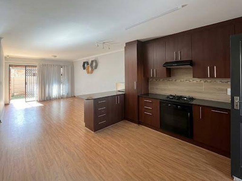 Spacious open-plan living area featuring a modern kitchen with dark wood cabinetry, granite countertops, built-in appliances, and direct access to the outdoor patio.