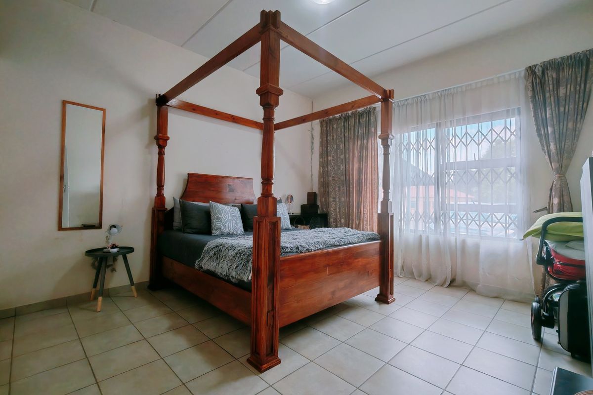 A bedroom featuring tiled flooring and a window fitted with a security gate, providing natural light and ventilation.