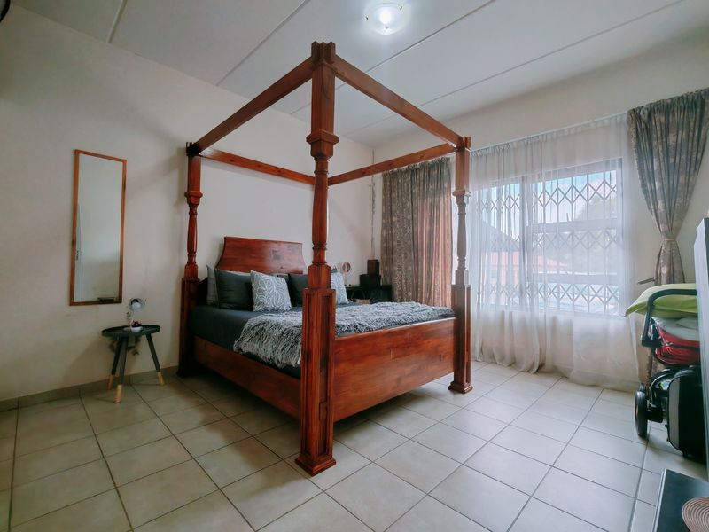 A bedroom featuring tiled flooring and a window fitted with a security gate, providing natural light and ventilation.