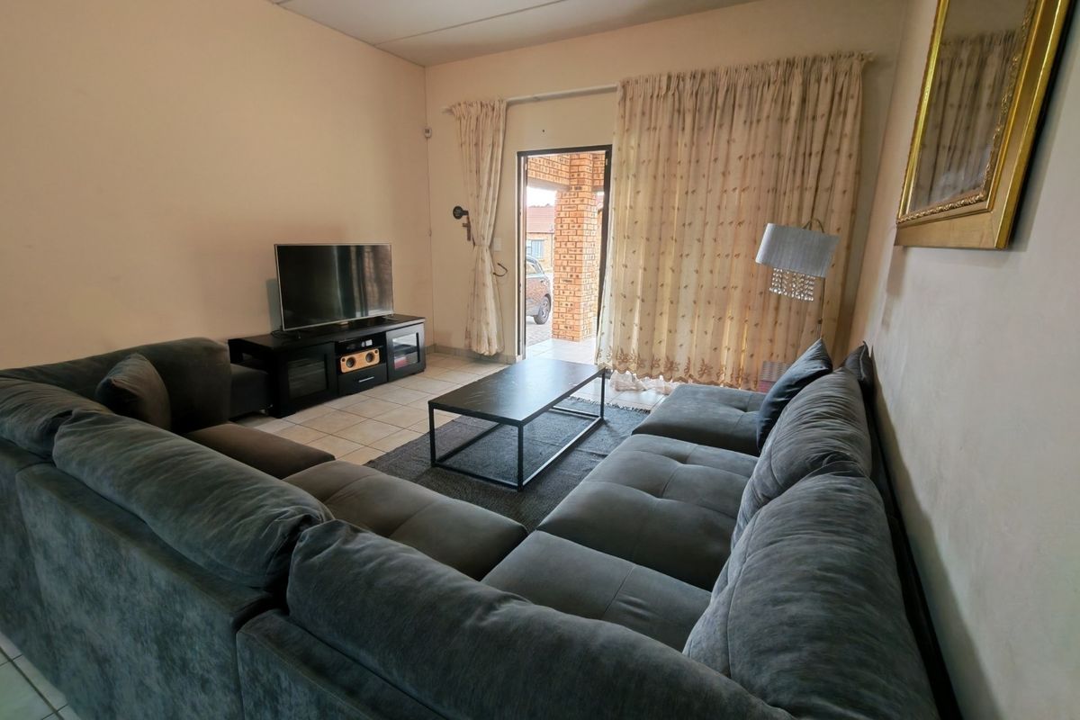 A comfortable living room featuring tiled flooring and a sliding glass door providing access to the exterior.