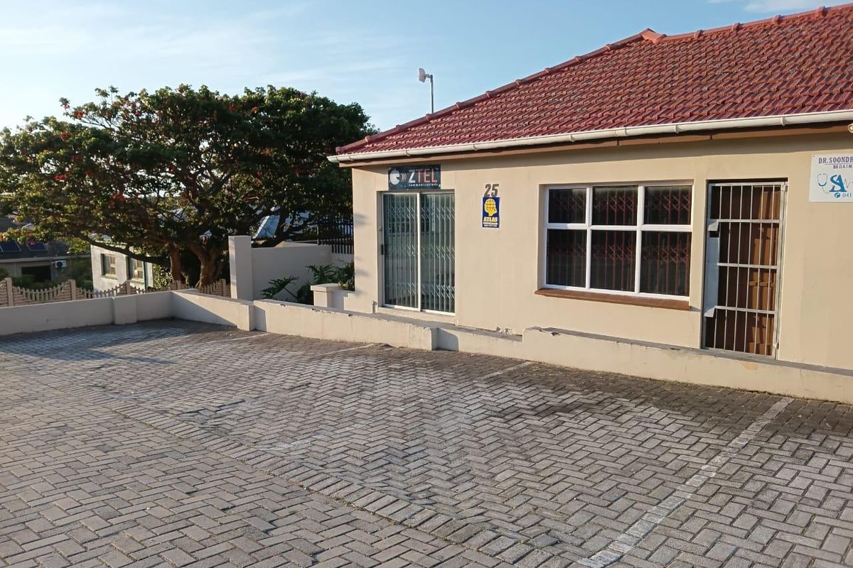 Front exterior view of a commercial property featuring a paved parking area, security gates, and tiled roof structure.