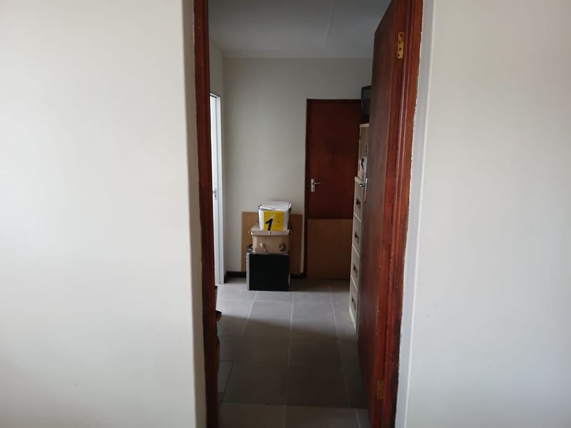 A functional hallway featuring tiled flooring and wooden door frames, providing access to adjacent rooms within the commercial property.