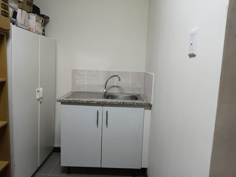A functional scullery area featuring a stainless steel sink, granite countertop, tiled splashback, and built-in cabinetry for convenient storage and utility.
