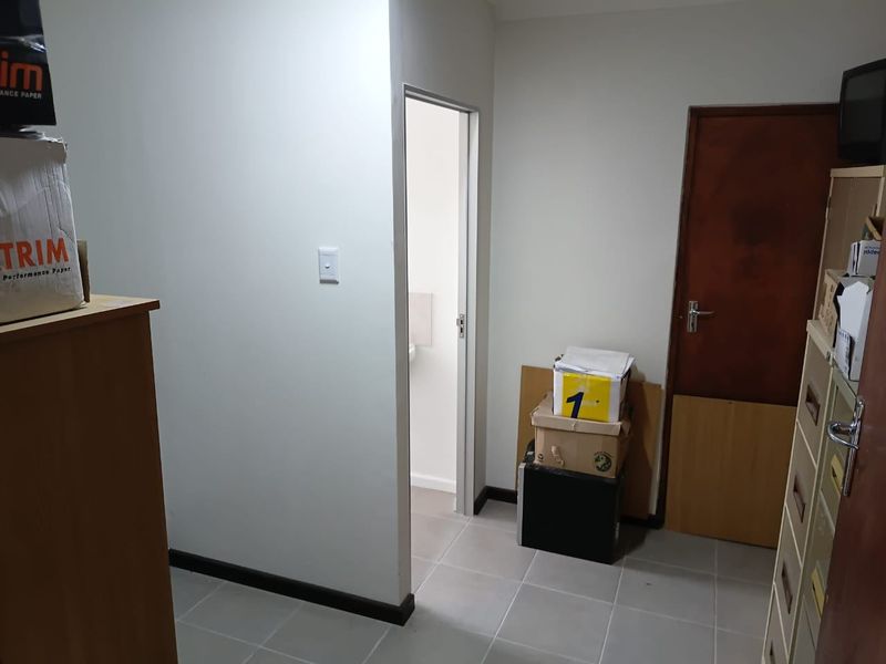 A functional hallway space featuring tiled flooring and access to an adjoining room, providing a neutral transition area within the commercial property.